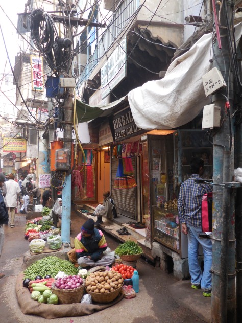 Vendors sell their wares along a street in Old Delhi. The tangle of wires above them are not defunct; electricians in Delhi know perfectly well where each one leads.